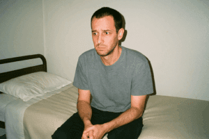 Mr. J sitting anxiously on a rehab room bed during his first days in Thailand.