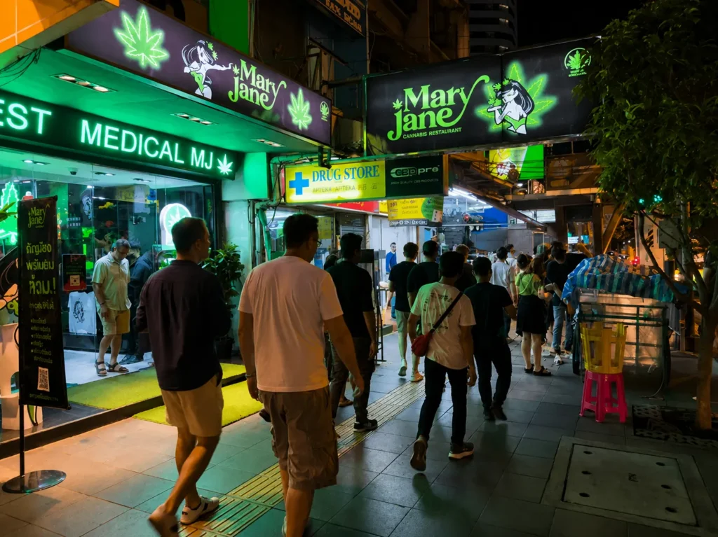 Nightlife street in Thailand with cannabis shops and tourists walking at night