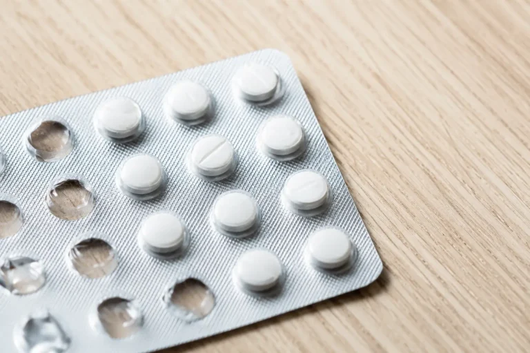 Osittain käytetty lääkeläpipainopakkaus valkoisilla tableteilla puisella pinnalla