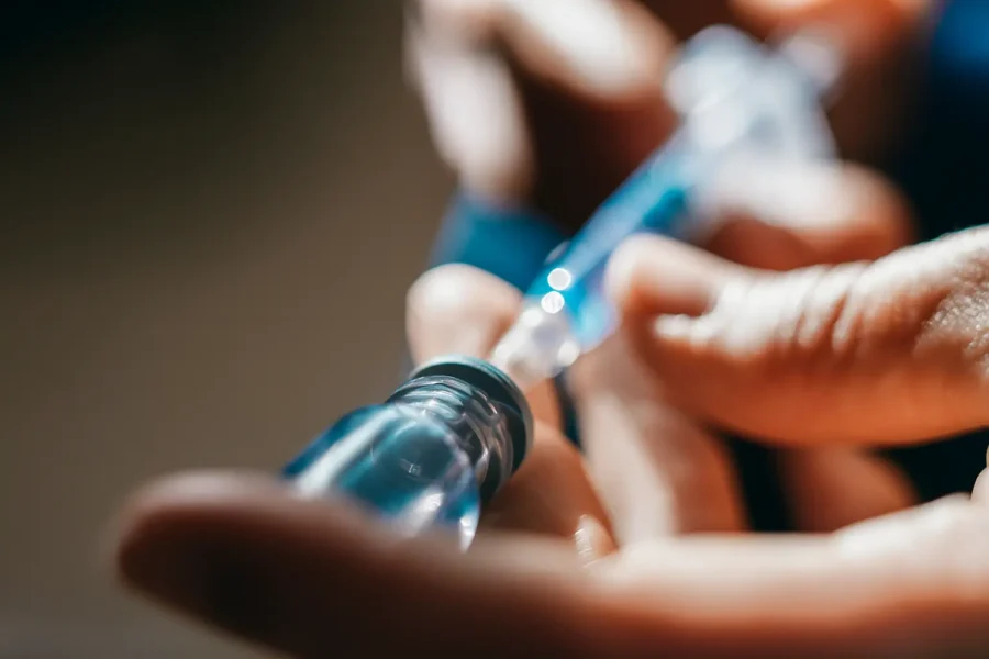 Close-up of hands preparing a syringe, symbolizing the dangers and dependency associated with cocaine addiction.
