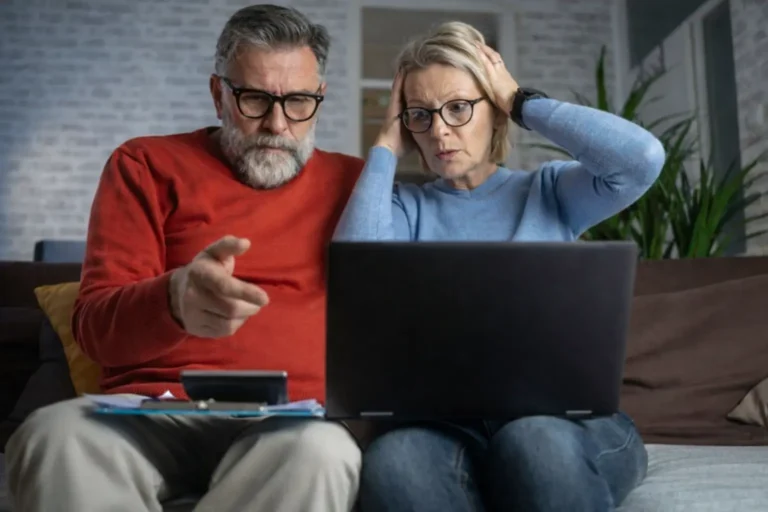 A concerned couple evaluating the trade-offs between privacy, costs, and professional reputation while researching private addiction treatment options on a laptop.