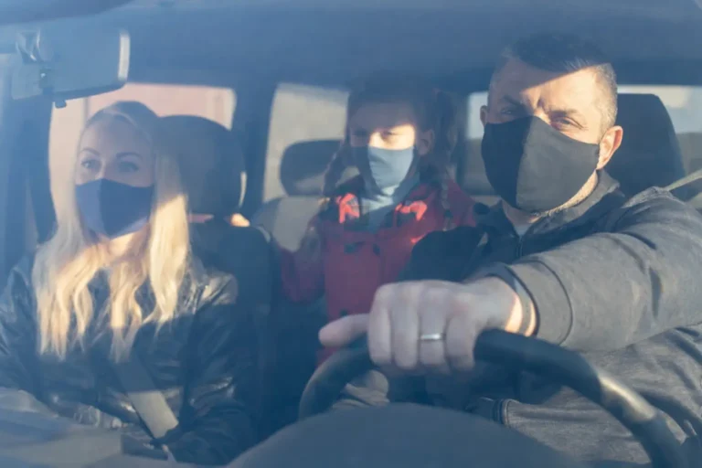 A family wearing protective masks in a car, representing the tension and safety decisions when navigating an addiction crisis.