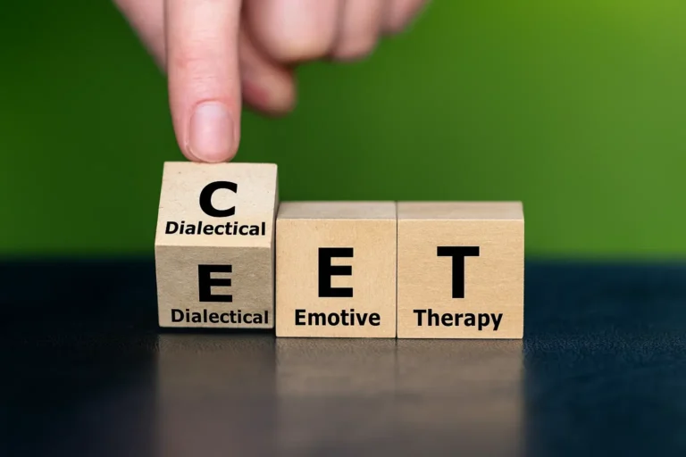 A hand adjusts wooden letter blocks arranged on a table.