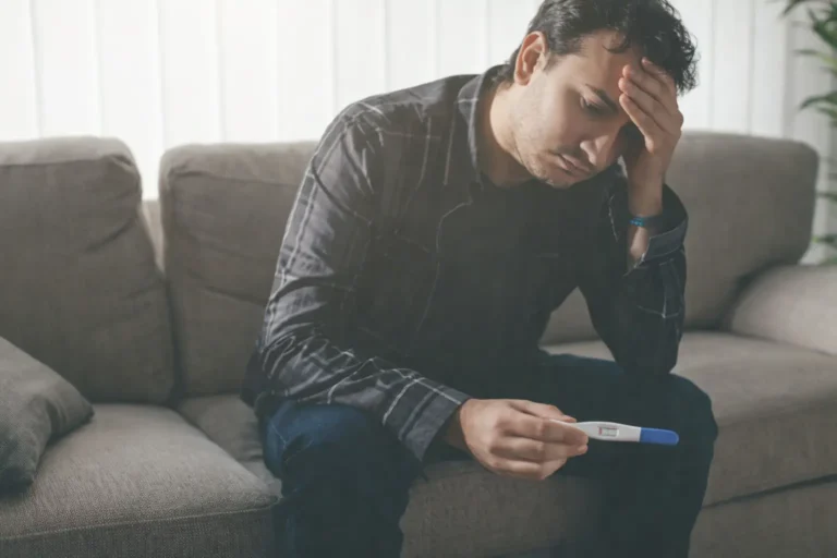Stressed man sitting on a sofa checking a rapid drug test result as part of home aftercare monitoring