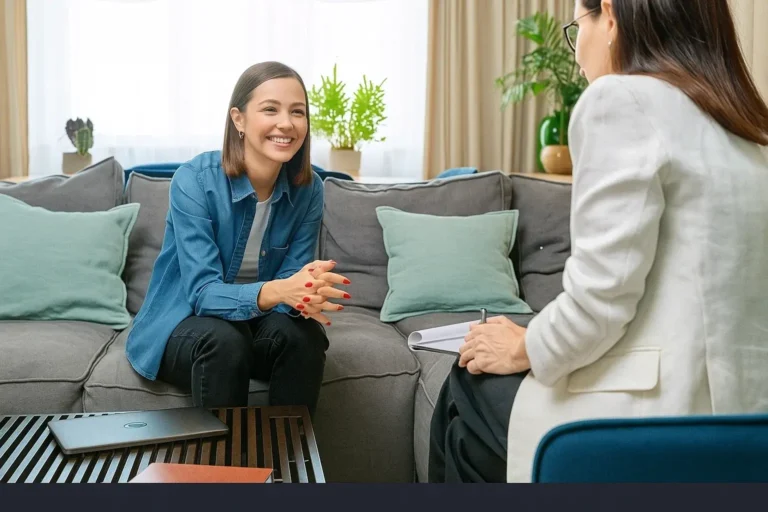 Person seated on a couch facing another individual in a conversation setting.