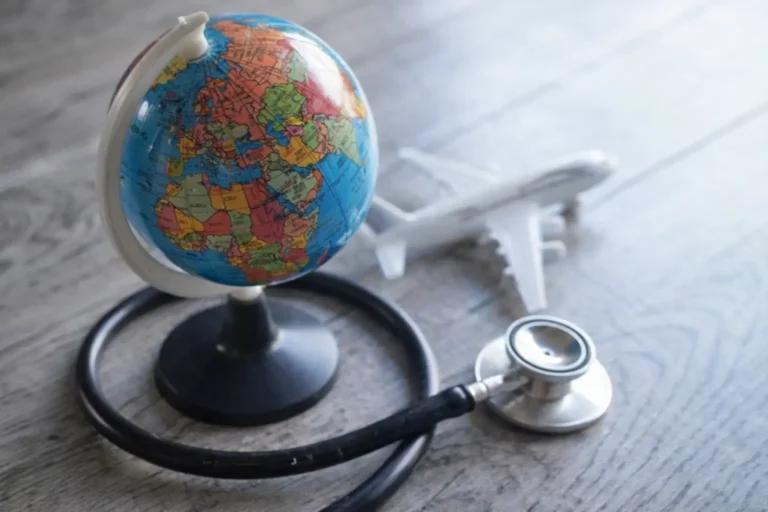A stethoscope is wrapped around the base of a globe with a model airplane in the background, symbolizing the logistics of international medical travel for rehab.