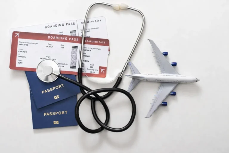 Top-down view of a stethoscope encircling two blue passports, boarding passes, and a miniature airplane on a white background.