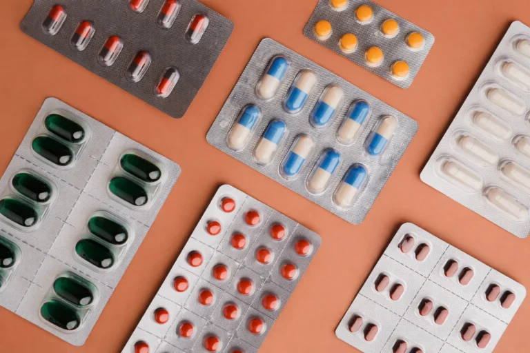 Assorted prescription medications in blister packs arranged on a neutral background.