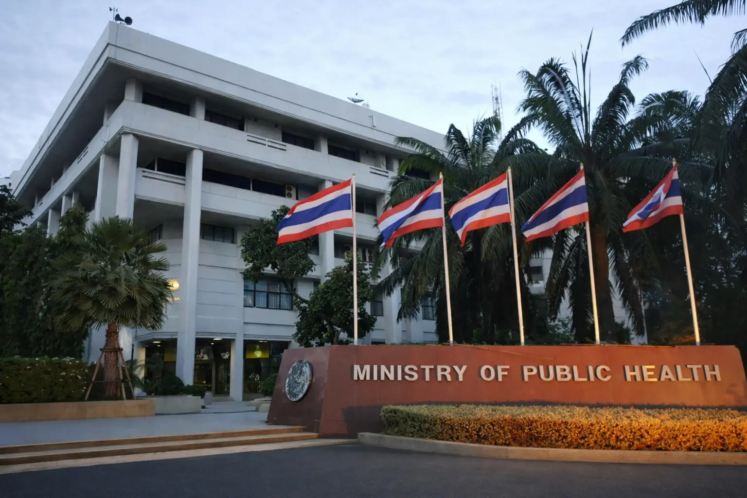 The Ministry of Public Health building in Thailand featuring a large entrance sign and flags, symbolizing medical regulation.