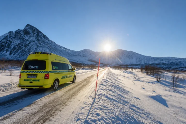 Norsk ambulanse på snødekt fjellvei i Nord-Norge