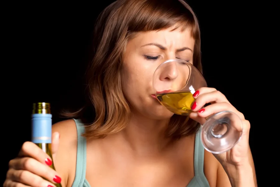 Young woman drinking wine while holding a bottle, representing polysubstance use with alcohol and its risks.