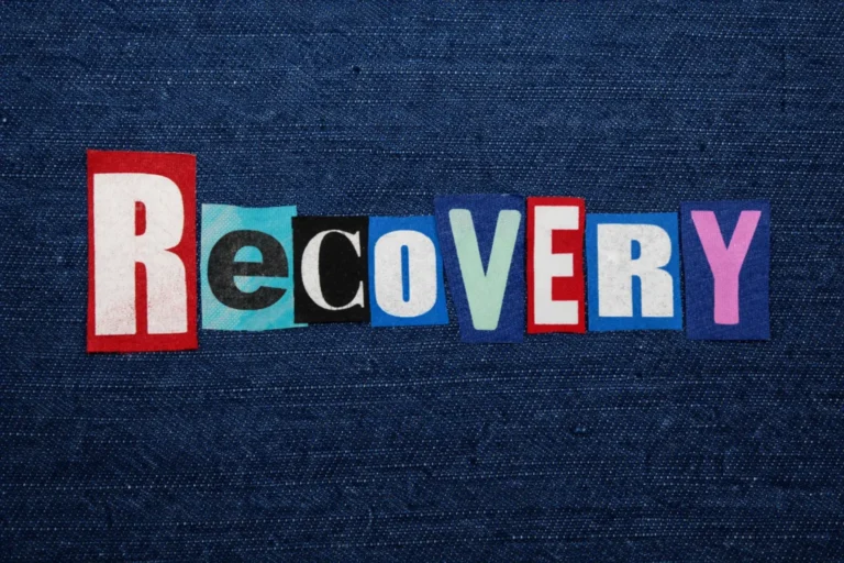 The word “Recovery” spelled with cut-out letters arranged on a denim background, representing addiction rehabilitation and sustained behavioral change.