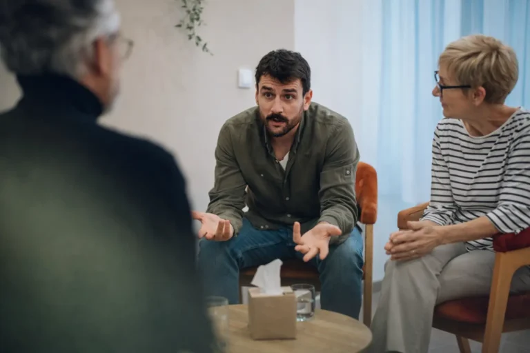 Three adults seated in a consultation setting discussing treatment planning and rehabilitation costs.