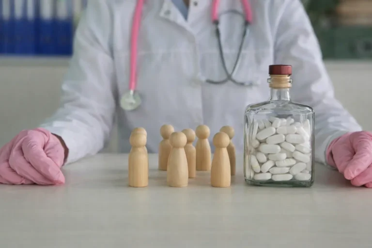 Doctor monitoring a bottle of pills and wooden figures, representing the transition from acute detox to long-term recovery.